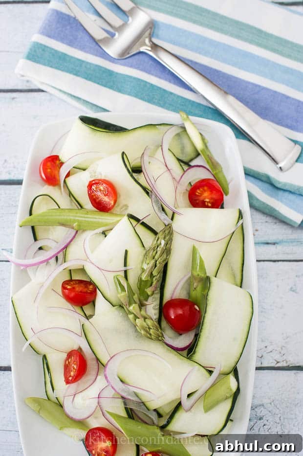 A sliced cucumber salad made of cucumbers, asparagus, red onion, and tomatoes, with light dressing.