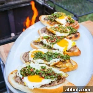 side view of buns layered with ground sausage, egg, and chimichurri on a plate