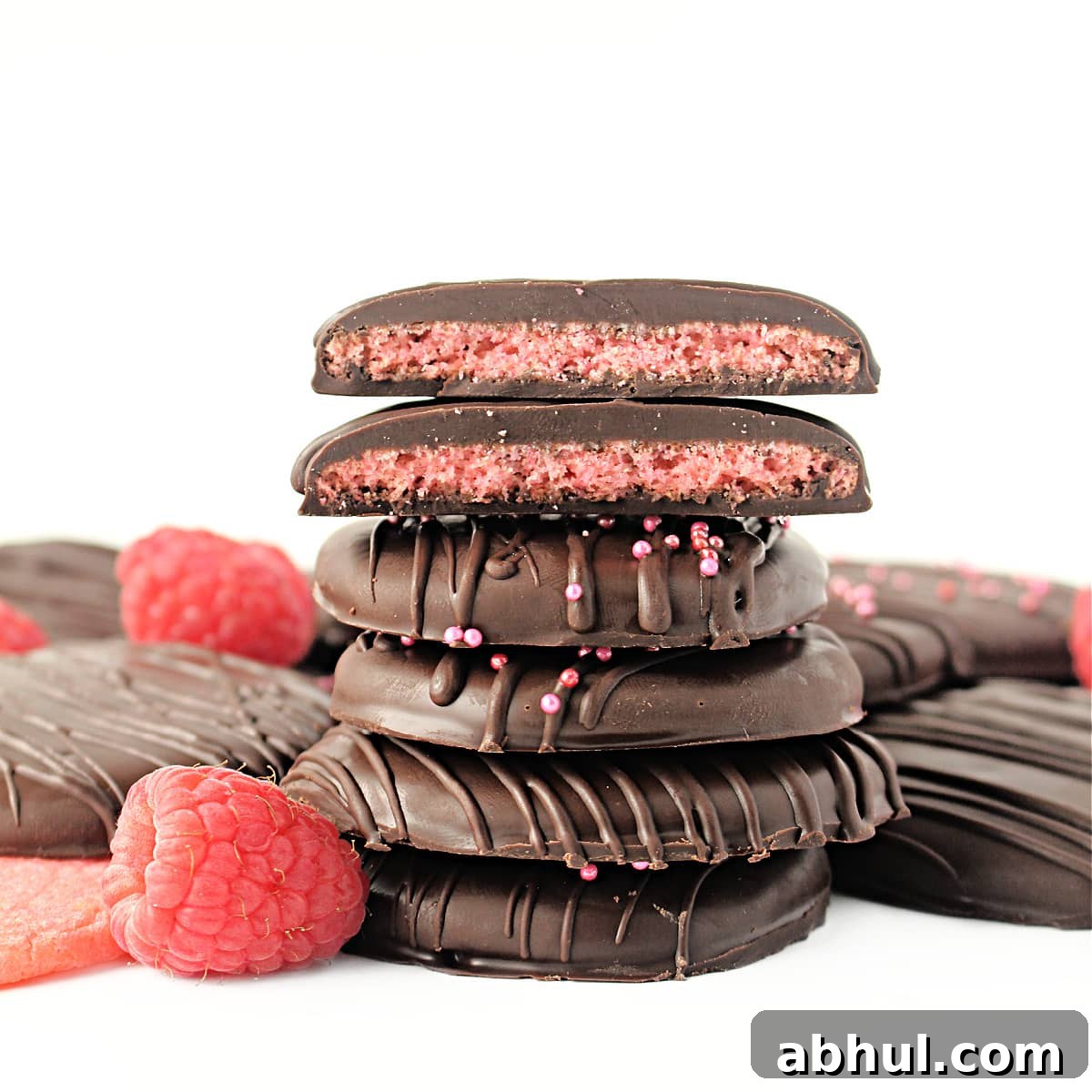 Stack of chocolate coated cookies with two cookie halves on top showing pink cookie inside.