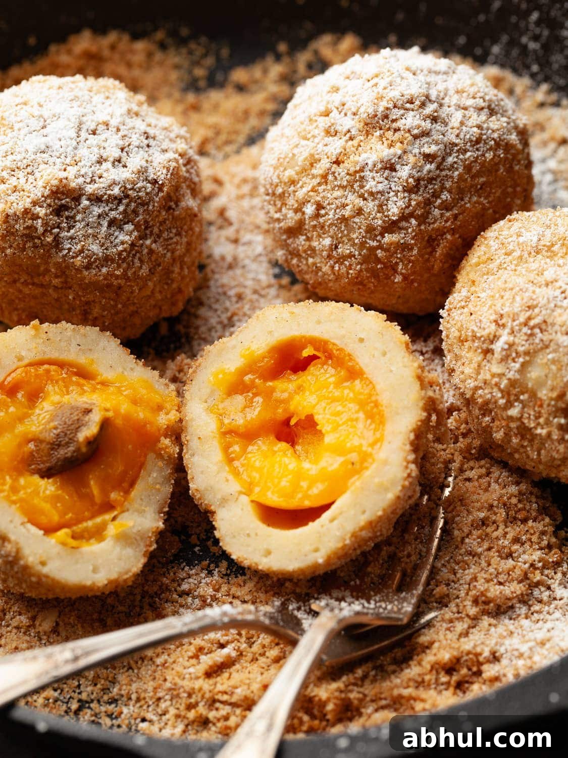 gluten free austrian apricot dumplings covered with bread crumbs and powdered sugar in a cast iron pan