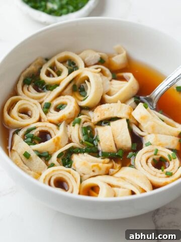 Gluten Free Frittatensuppe topped with fresh chopped chives and served with a beef broth in a bowl