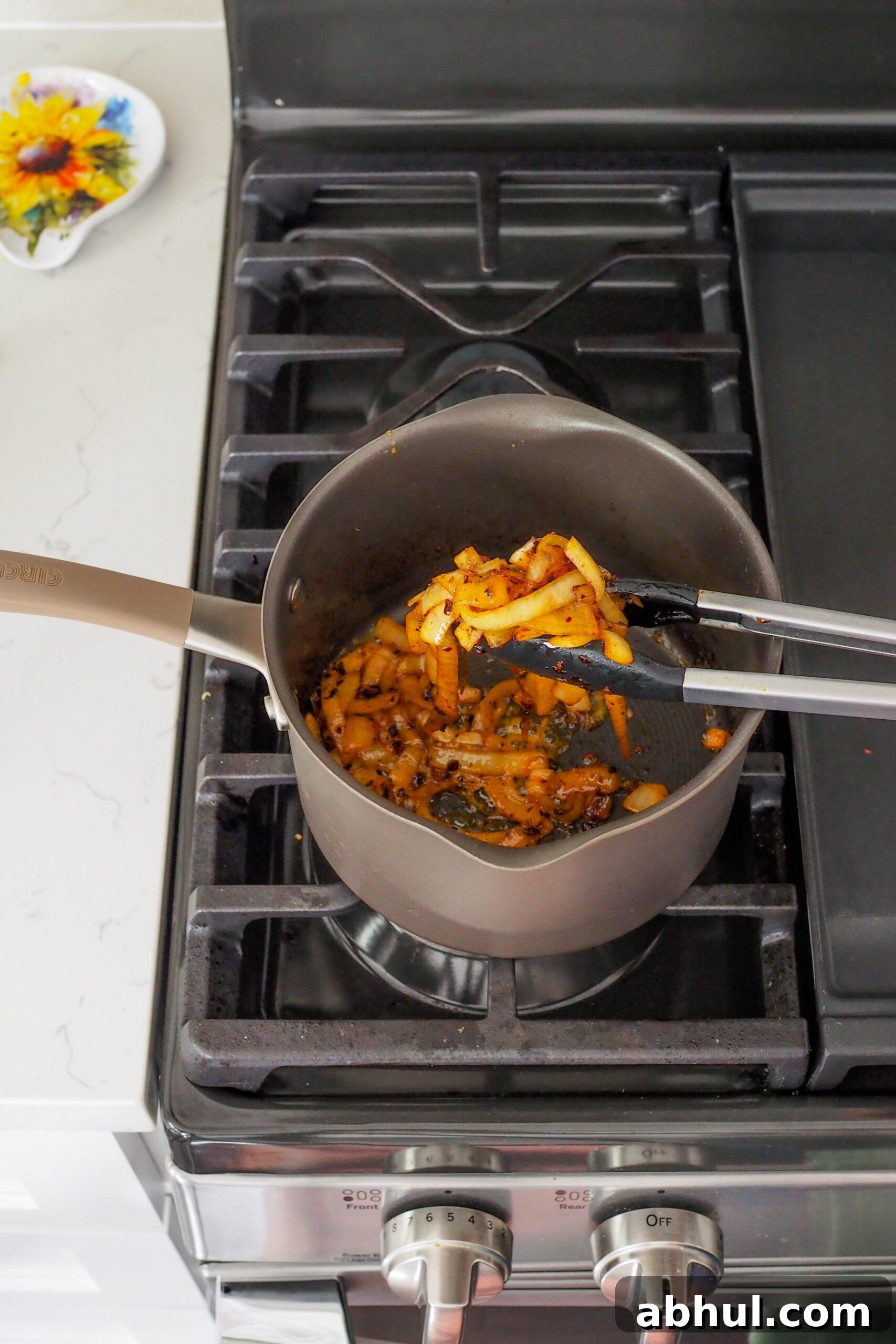 Spicy Gochujang Chicken Ramen Recipe for Quick Weeknights 6 A set of tongs holds up softened onion that has almost caramelized.