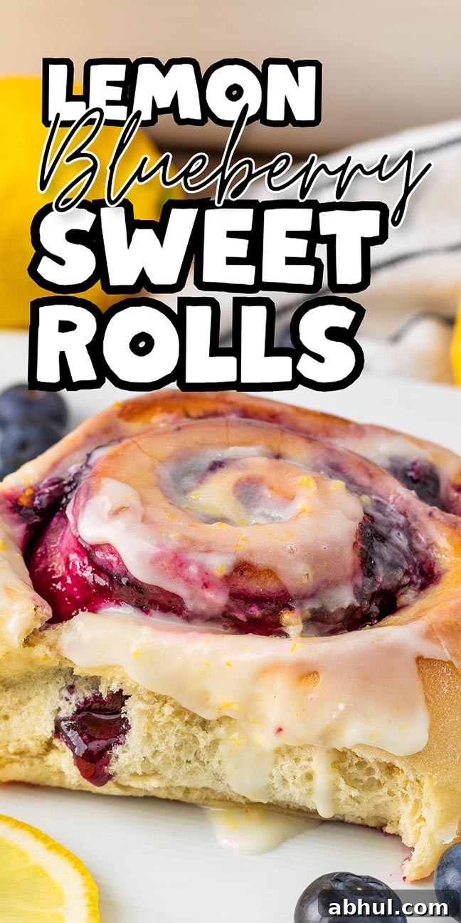 Close-up of lemon blueberry sweet rolls with icing, surrounded by fresh blueberries and juicy lemon slices.