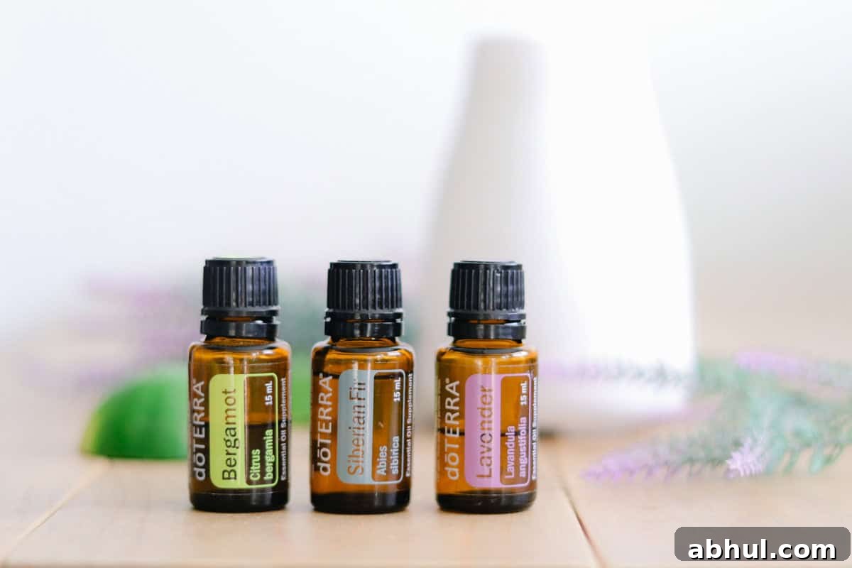 Three essential oil bottles on a wooden table with a white diffuser behind them. 