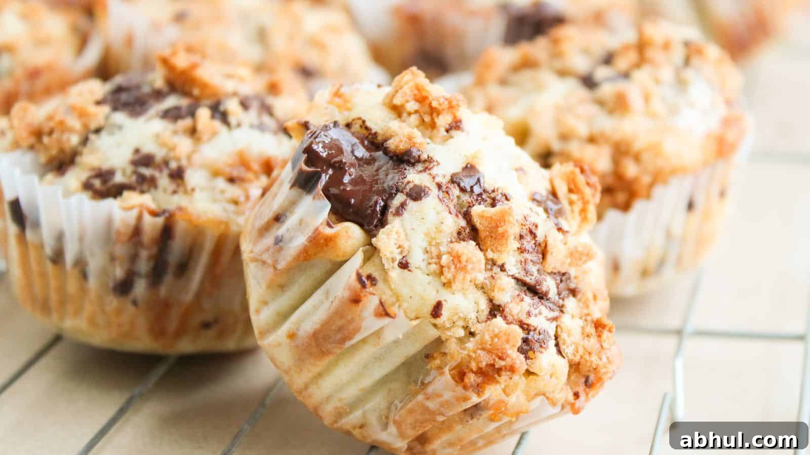 Close-up of chocolate chip muffins with crumb topping in paper liners, cooling on a wire rack.