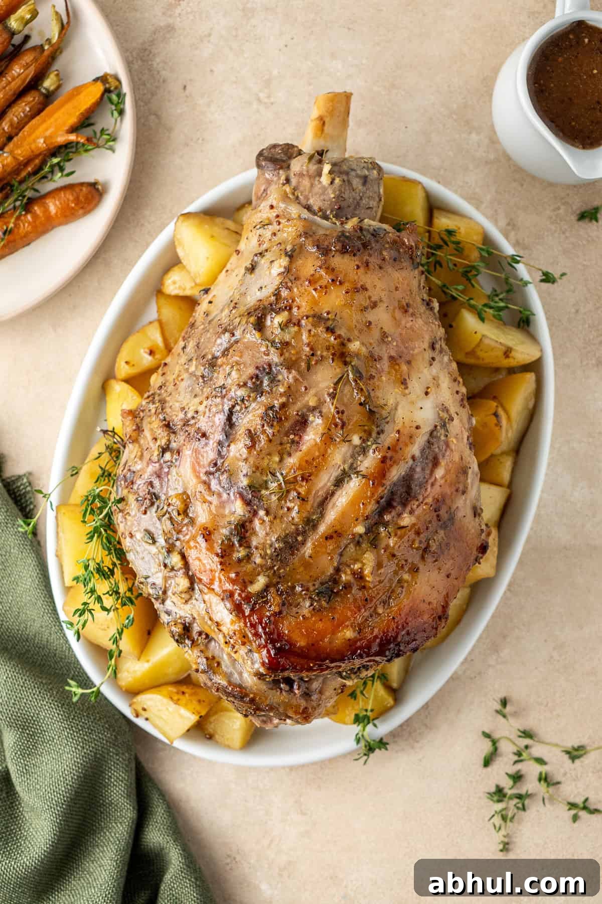 The glazed roast leg of lamb on a plate with potatoes.