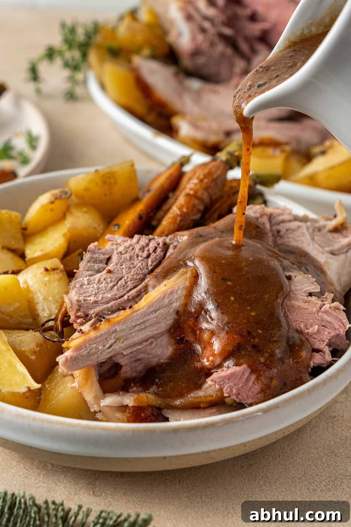 Pouring gravy over the roast lamb.