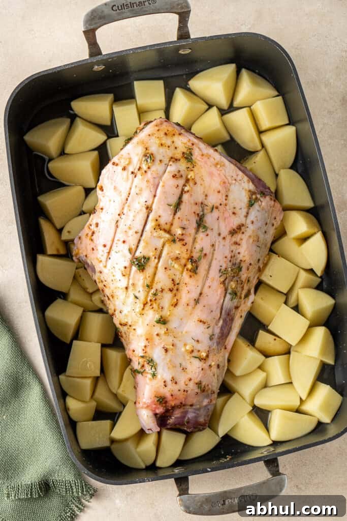 The roast lamb and potatoes in the baking dish ready for the oven.
