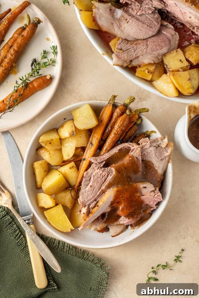 The roast lamb served on a plate with potatoes and carrots.