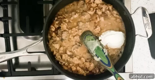 Cooking healthy turkey stroganoff with sour cream.