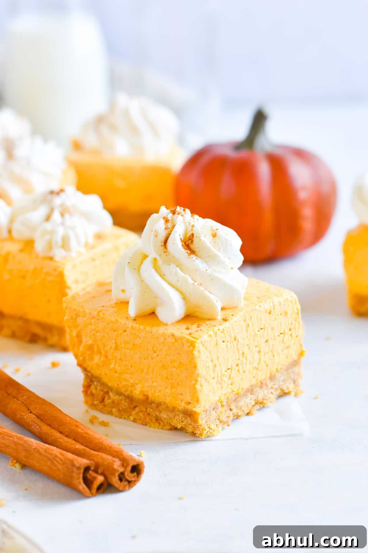 pumpkin cheesecake square with swirl of whipped cream on top.