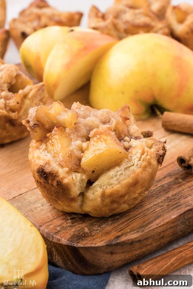 Mini Apple Pie Bites with Flaky Puff Pastry 9 A mini apple pie on a cutting board with an apple.