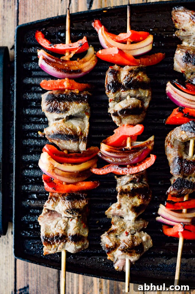 Beef Satay - Flank steak, red onions, red bell peppers on wooden skewers are on an Electric Grill.