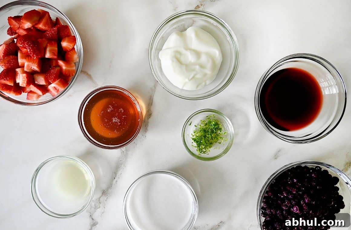 Small glass bowls containing the ingredients to make red, white and blue fruit popsicles