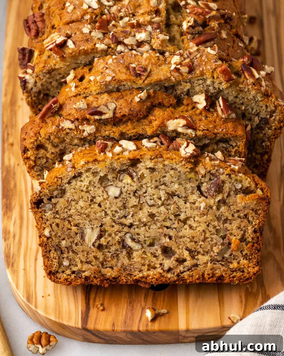 Slices of gluten free banana bread stacked on a wooden cutting board.