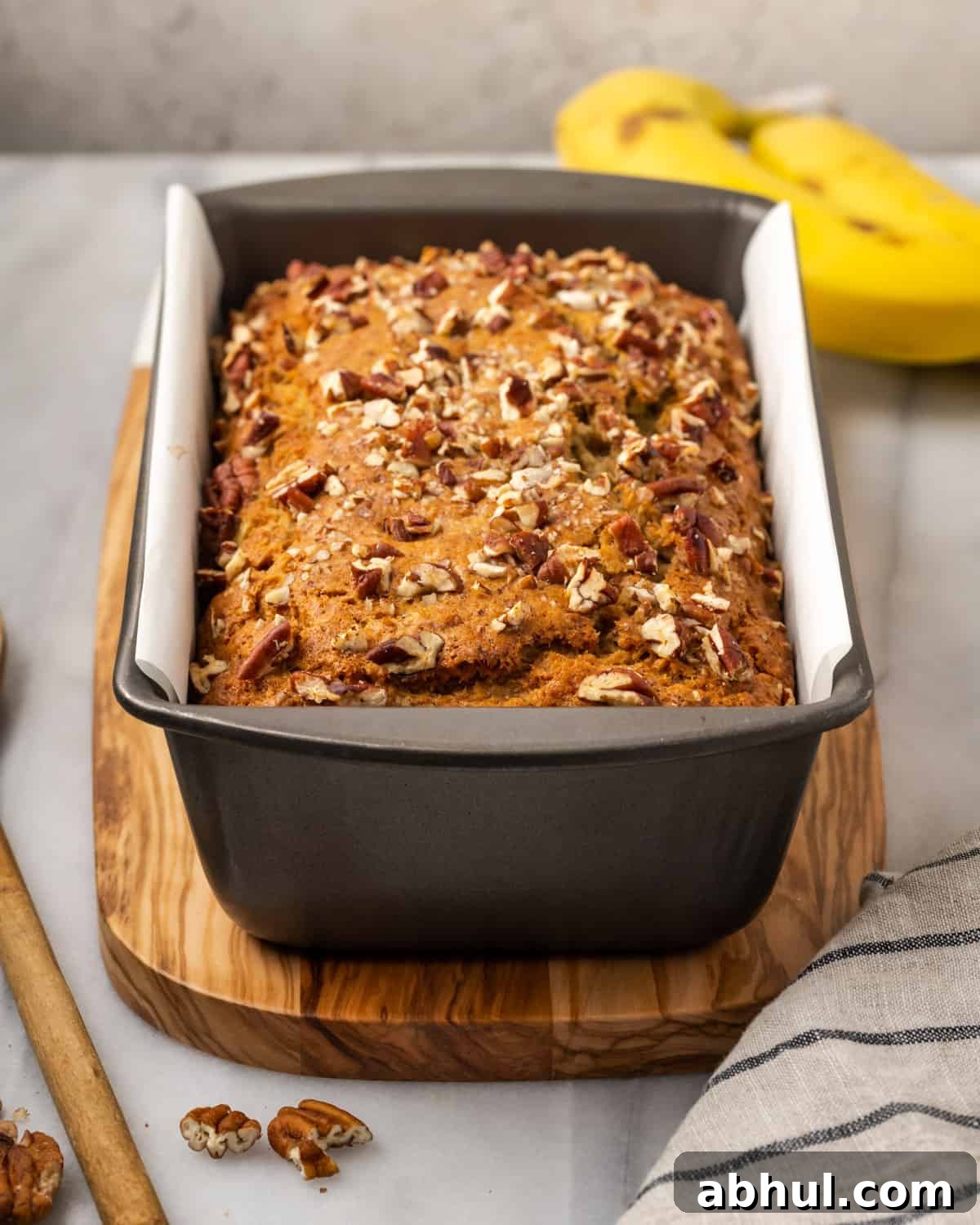 A freshly baked loaf of gluten free banana nut bread in a metal baking tin.