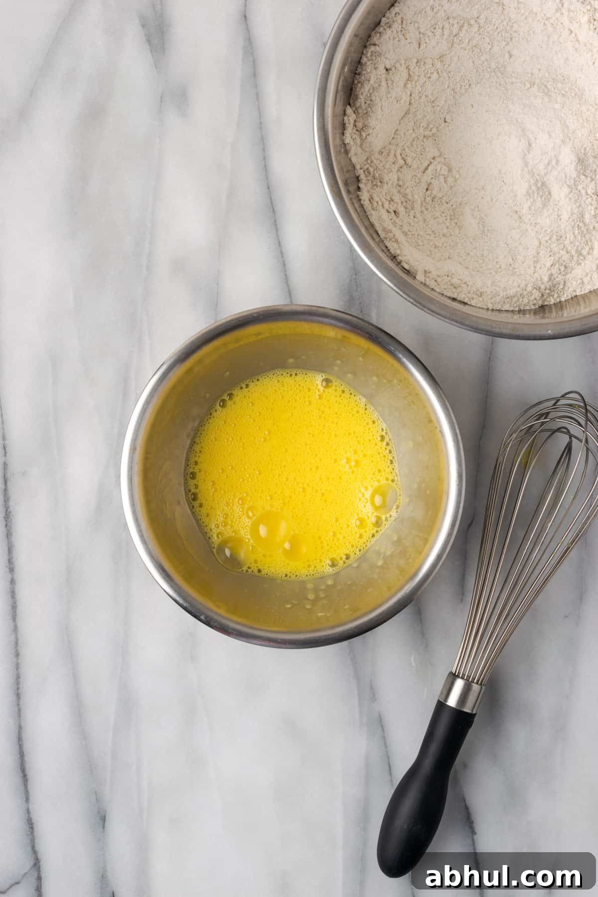Two eggs whisked until frothy in a small metal mixing bowl.