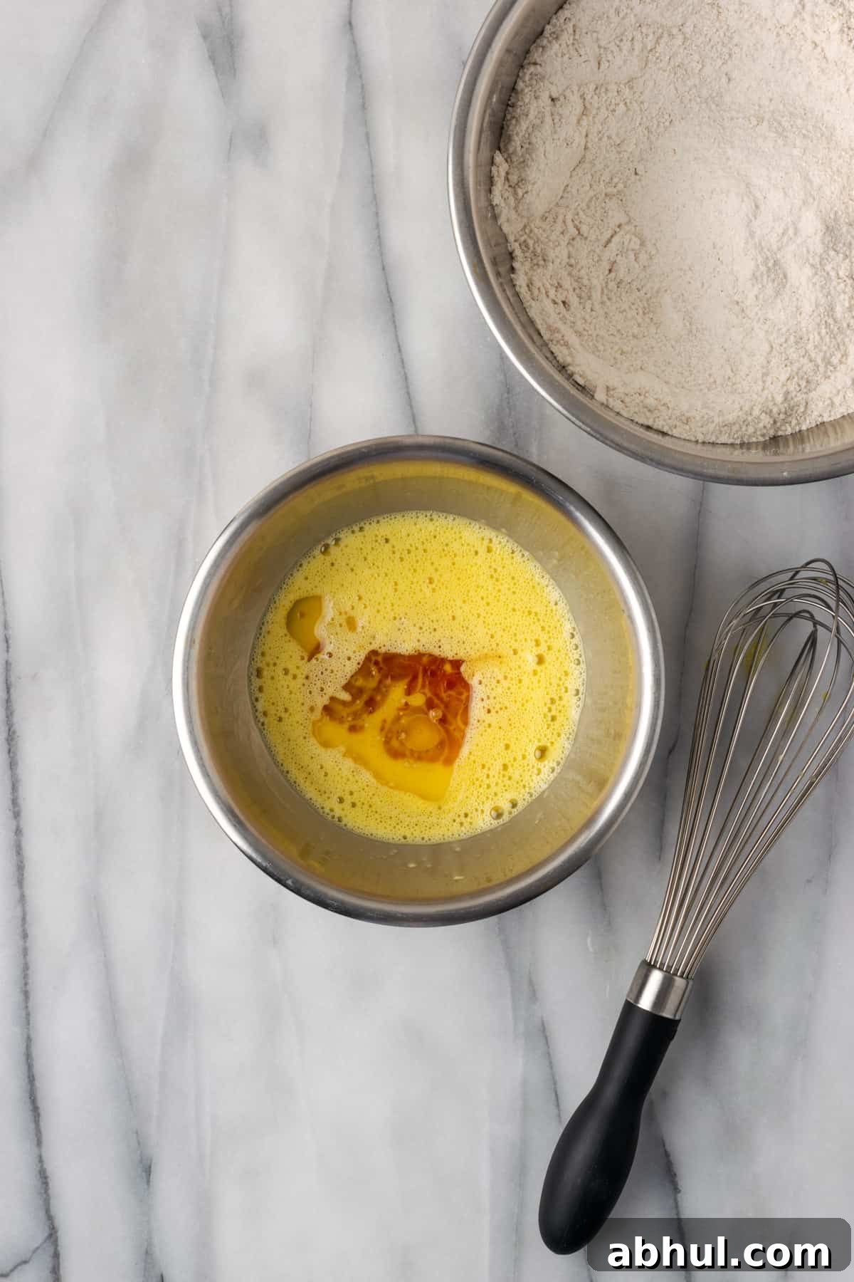 Oil and vanilla added to beaten eggs in a small mixing bowl.