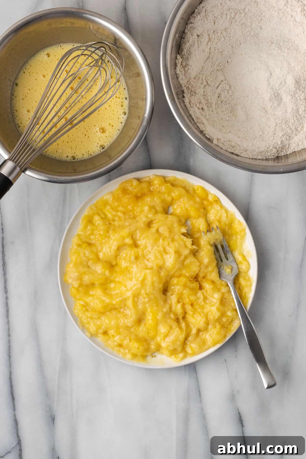 Three bananas mashed to a wet pulp on a white plate.