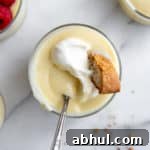 Homemade Gluten-Free Vanilla Pudding Recipe from Scratch 11 Close up of a bowl of vanilla pudding topped with whipped cream and a biscotti.