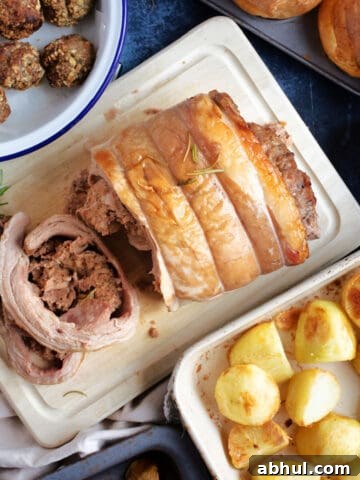 Slow cooker rolled lamb breast cut into slices with roast potatoes and stuffing.