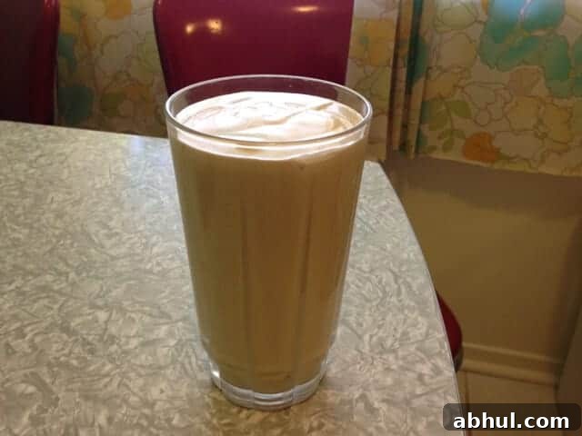 A glass of peanut butter banana smoothie on a table.