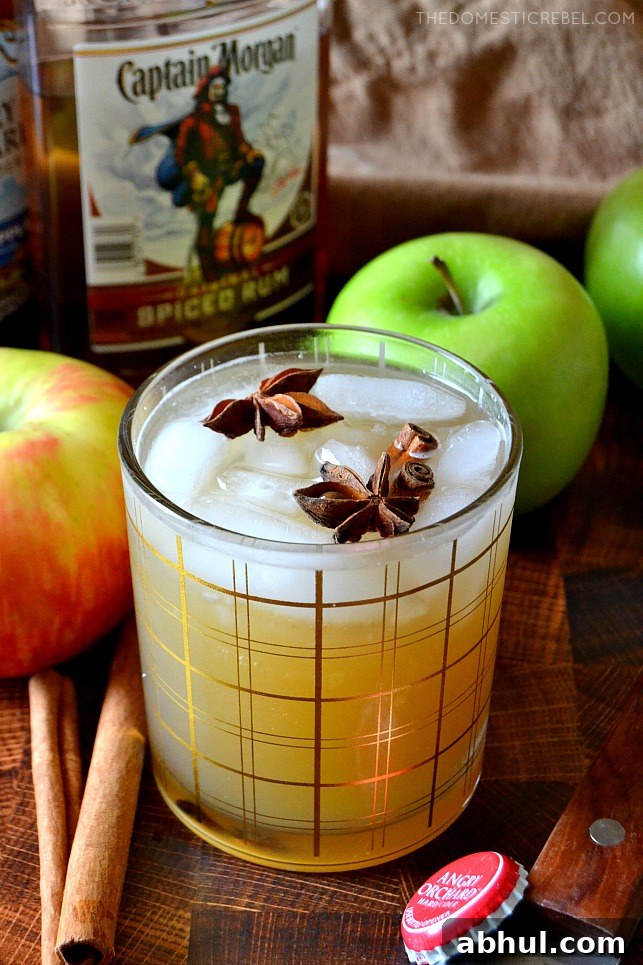 Apple Cider Spiced Rum Cocktail on wood background with rum and apples in background