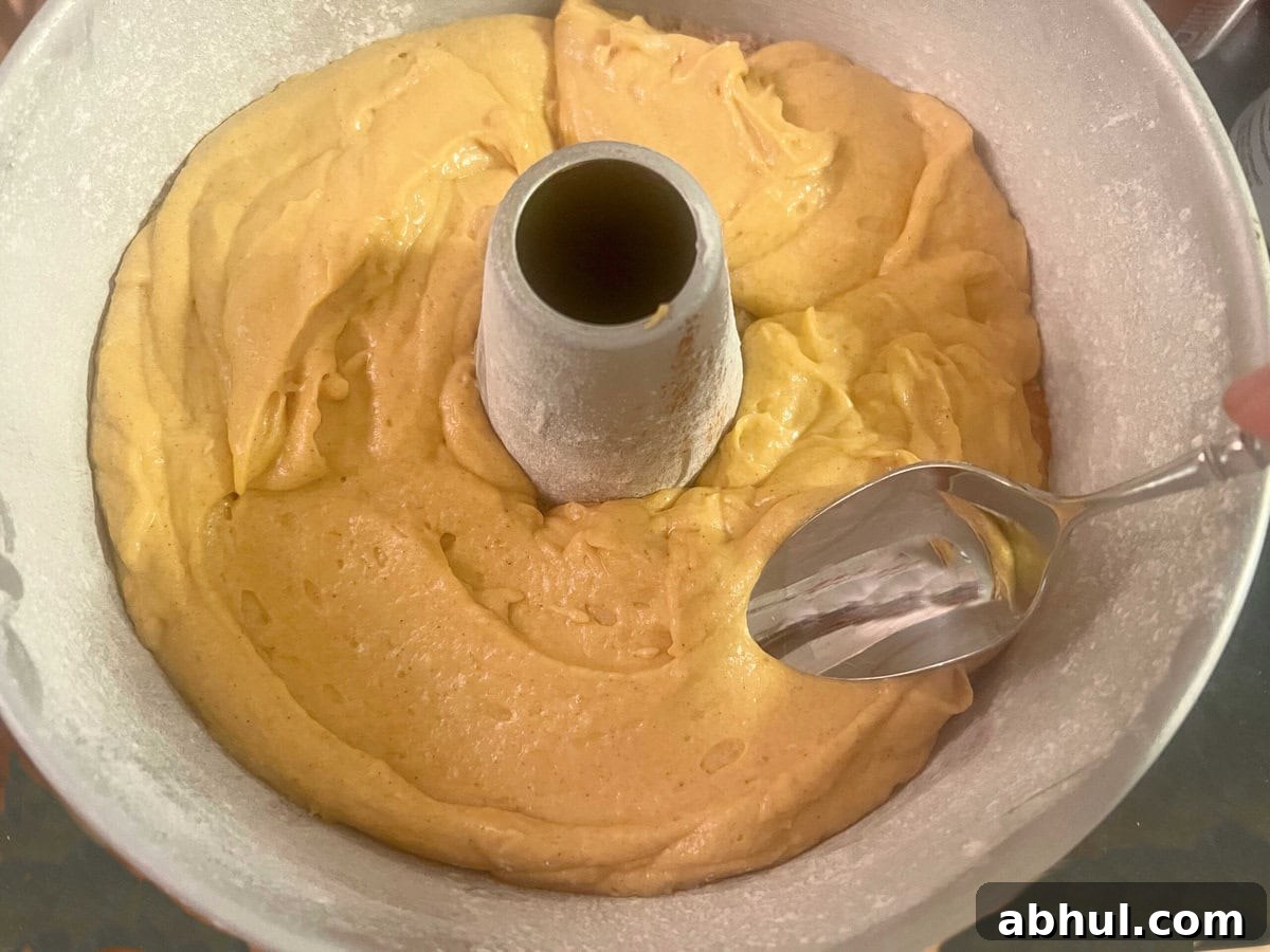 Smoothing the second half of the batter over the cinnamon and brown sugar mixture in the cake pan.