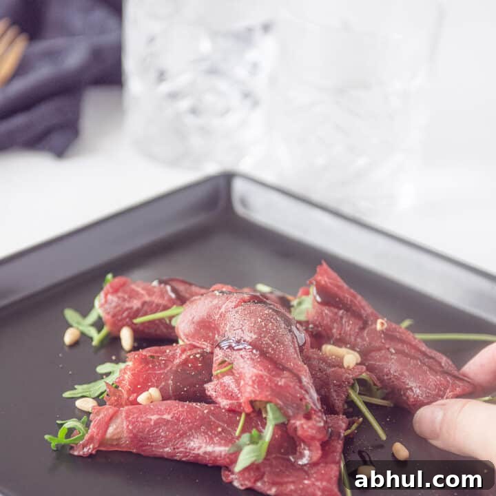 Beef carpaccio roll on a black plate