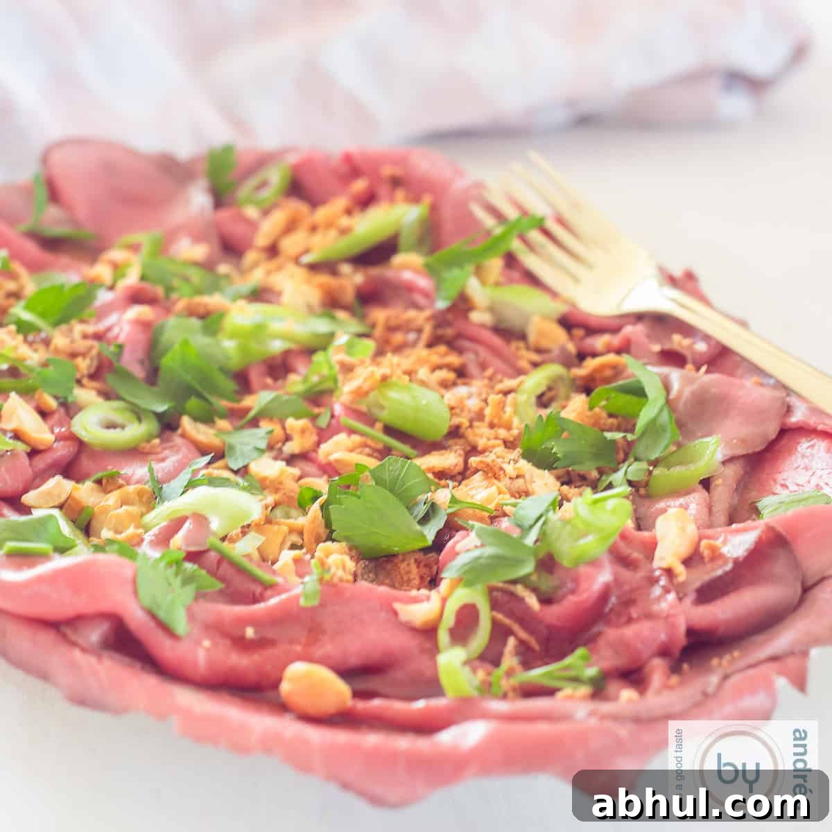 A square photo with a bowl filled with Asian style roast beef carpaccio salad.