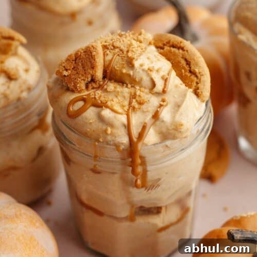 Pumpkin pie cups in mason jars, topped with crushed gingersnap cookies and drizzled cookie butter.