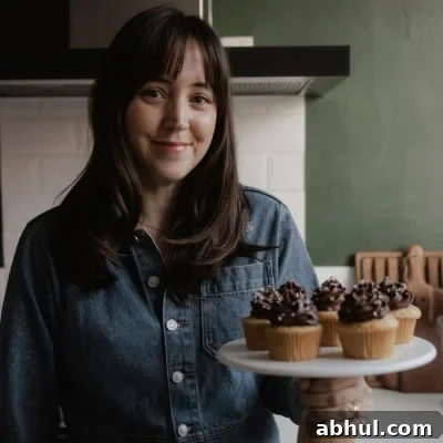 One-Bowl Pumpkin Sour Cream Muffins: Moist Fall Recipe 14 Ella from Alpine Ella is holding a cake stand with cupcakes on it.