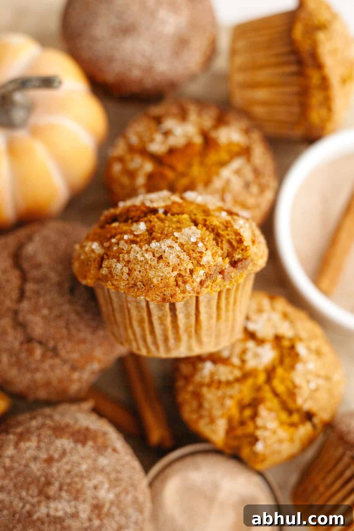 One-Bowl Pumpkin Sour Cream Muffins: Moist Fall Recipe 7 A close up of pumpkin muffins on parchment paper.