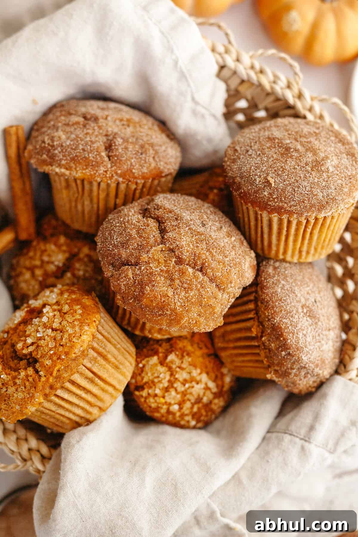 One-Bowl Pumpkin Sour Cream Muffins: Moist Fall Recipe 8 A basket filled with pumpkin muffins, topped with sparkling sugar.