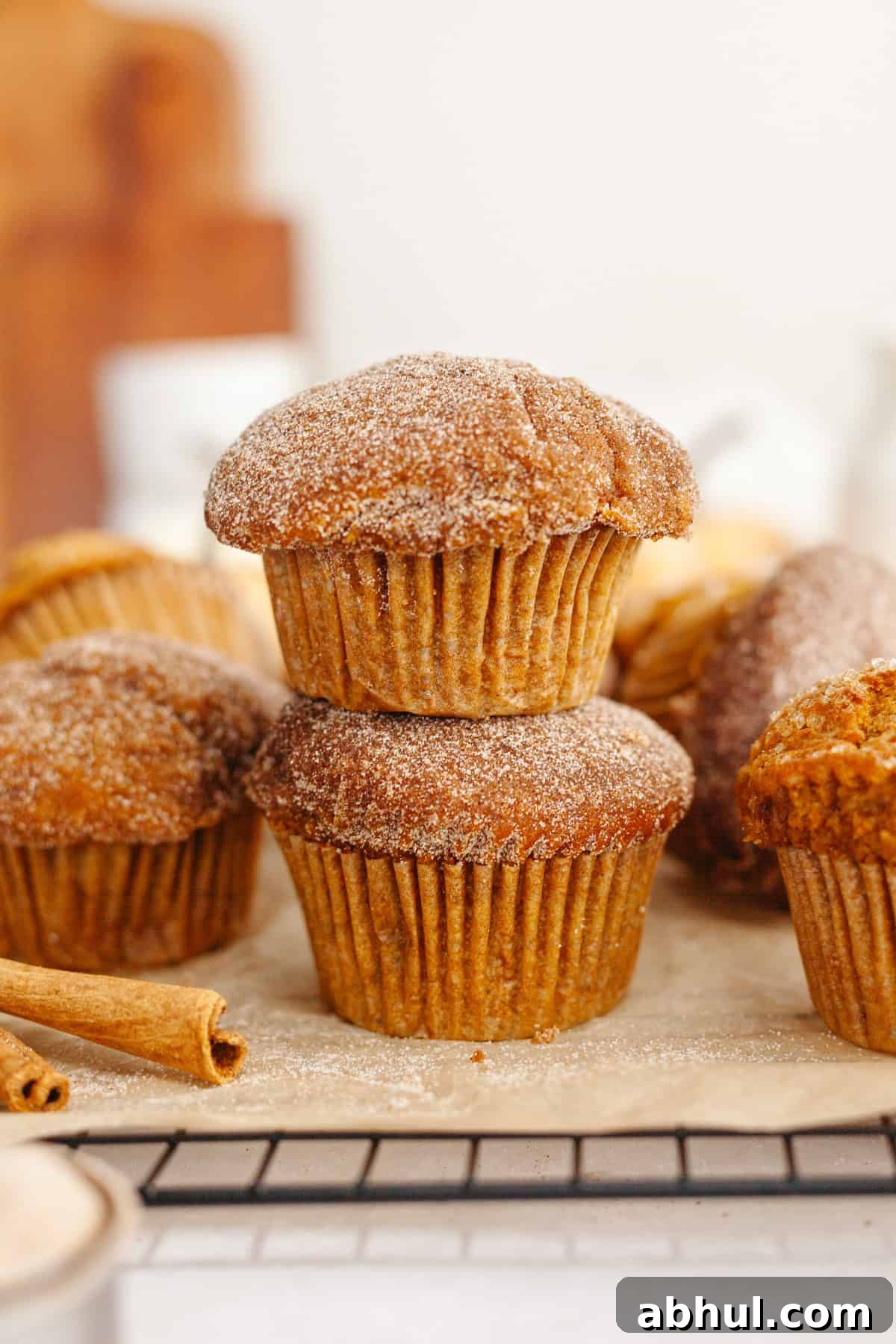 One-Bowl Pumpkin Sour Cream Muffins: Moist Fall Recipe 9 A stack of two pumpkin sour cream muffins covered in sugar.