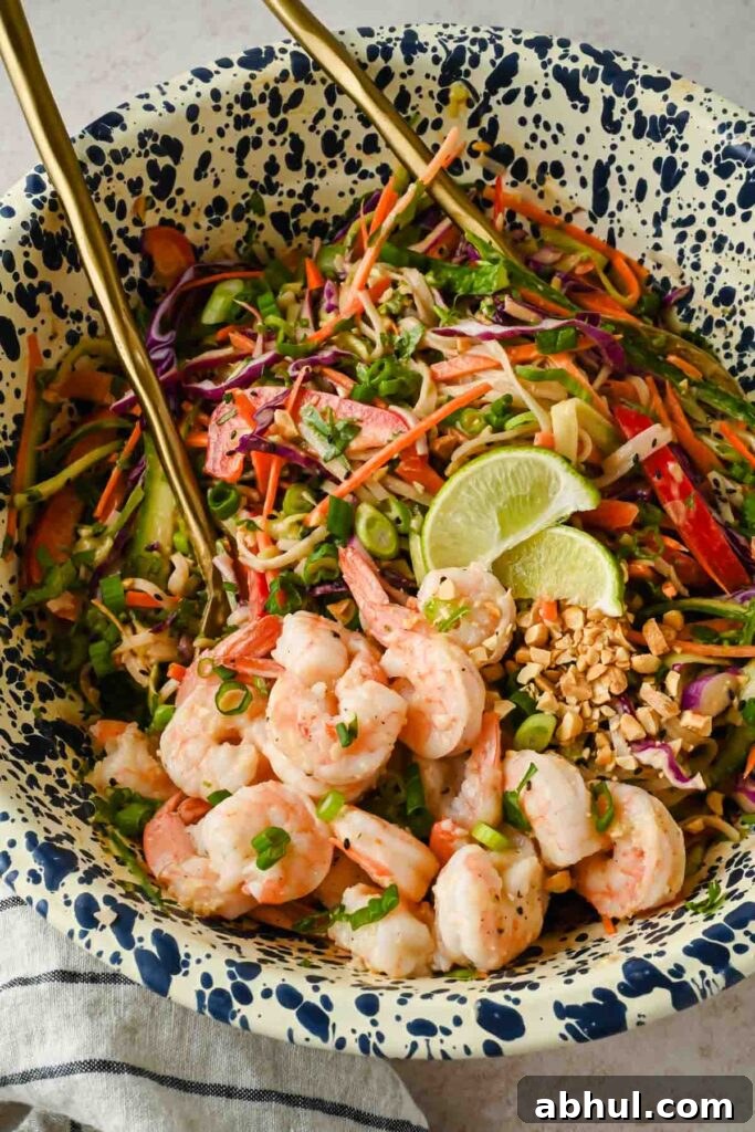 spring roll salad topped with fresh shrimp, chopped peanuts and a lime wedge in large mixing bowl.