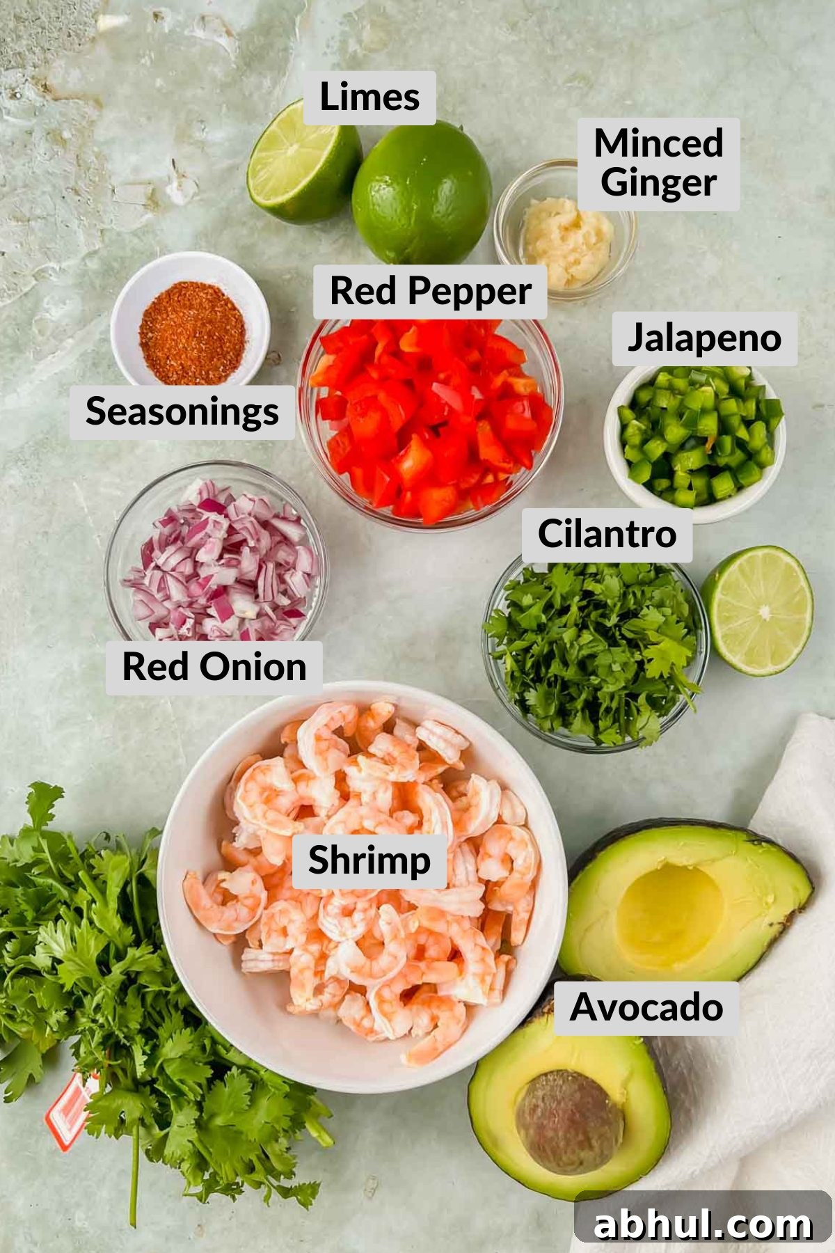ingredients for avocado shrimp ceviche in individual bowls on green background.
