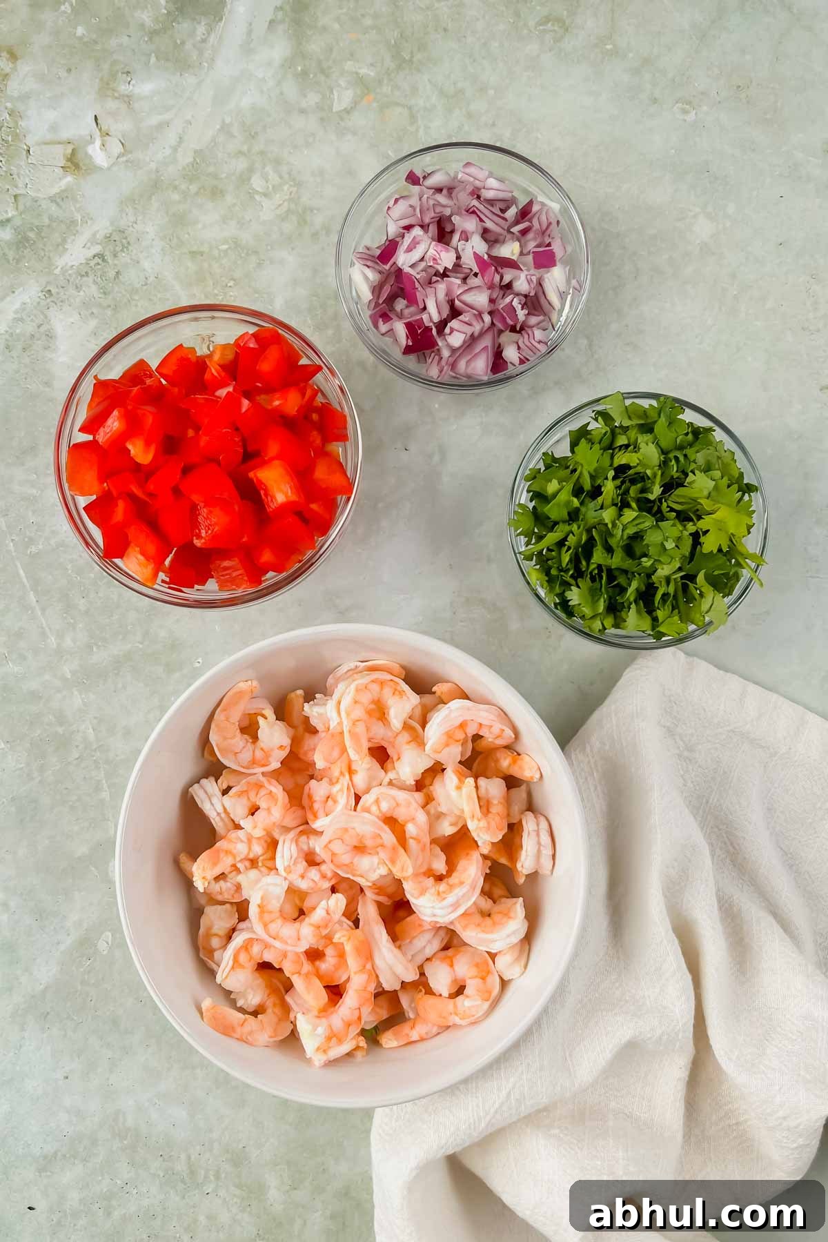 prepared vegetables and shrimp in individual bowls on green background.