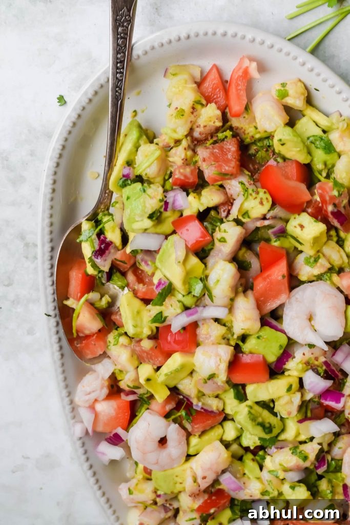 avocado shrimp ceviche salad on white serving dish on gray background.