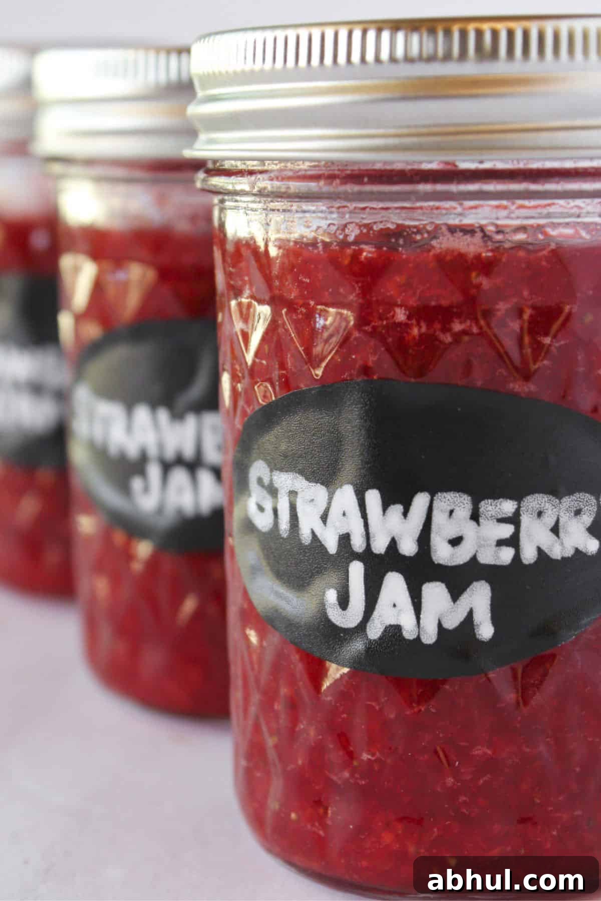 Three jars of strawberry jam without pectin in jars with lids and labels.
