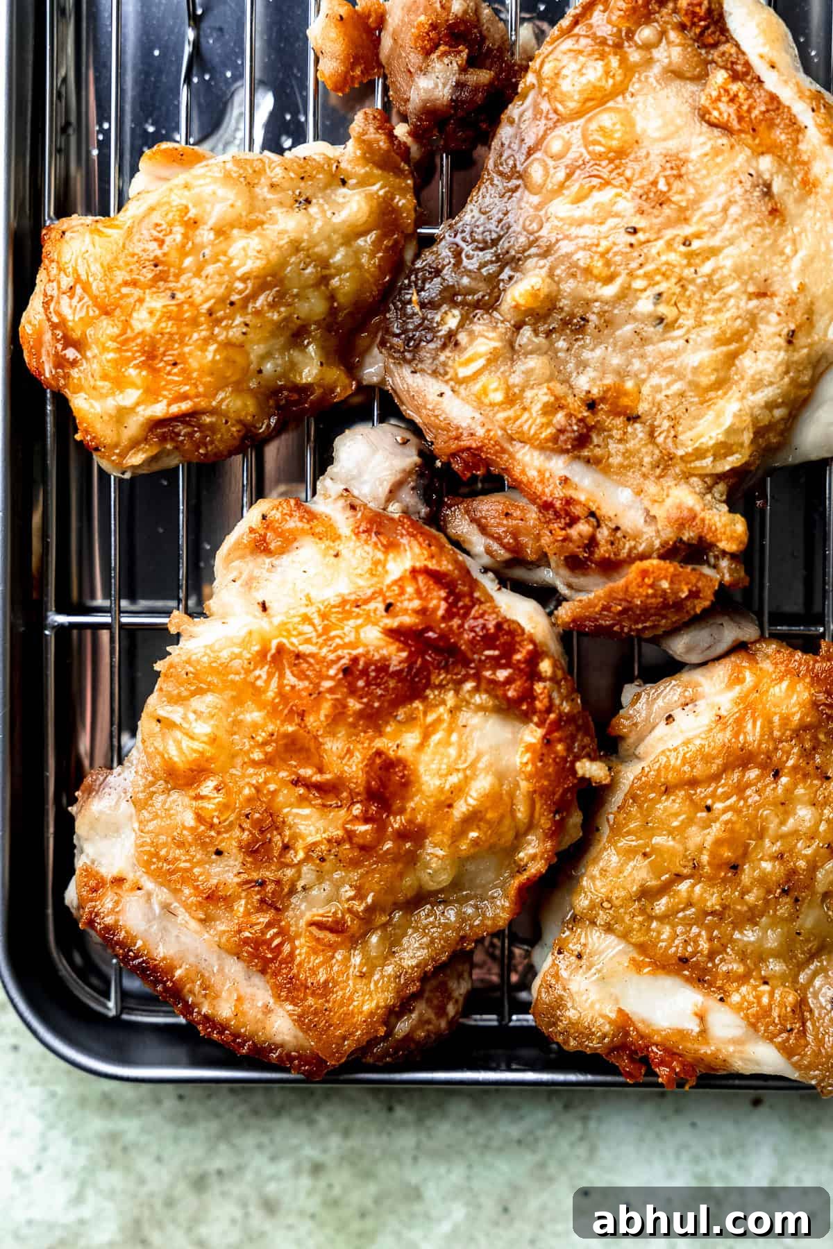 Crispy chicken thighs on a cooling rack.