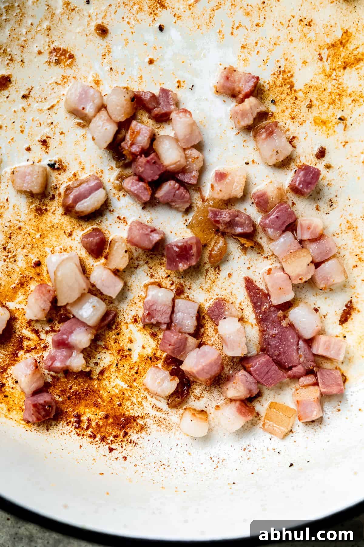 Bacon being cooked in a pan until crispy.