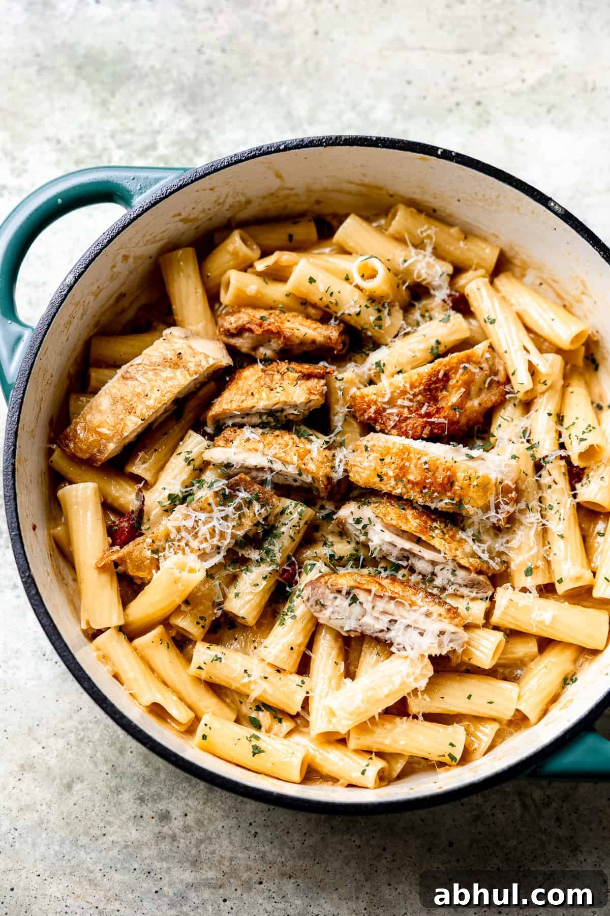 Chicken and bacon pasta in a pan with parsley and cream sauce.