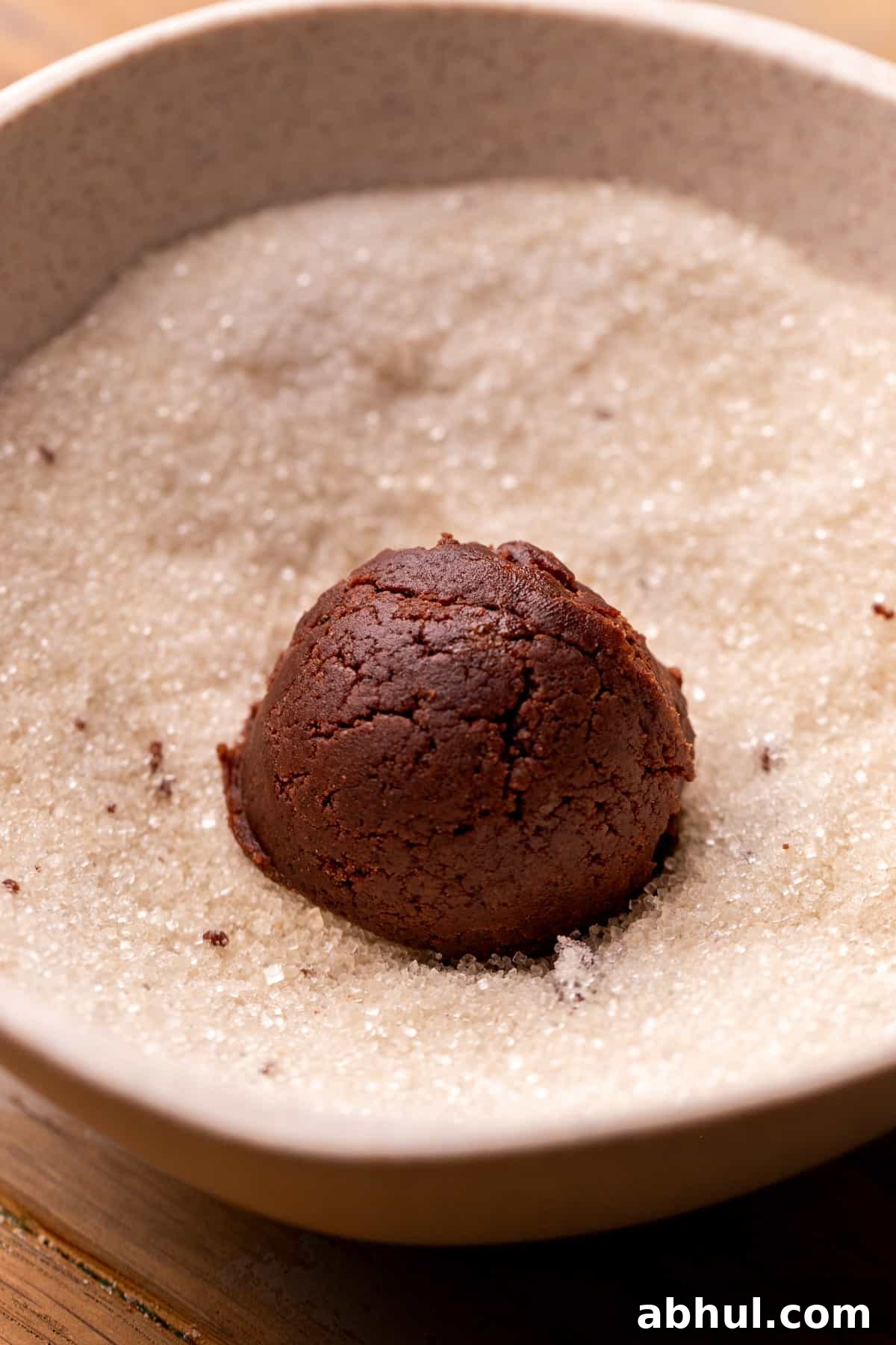 Cookie dough ball in a bowl of sugar.