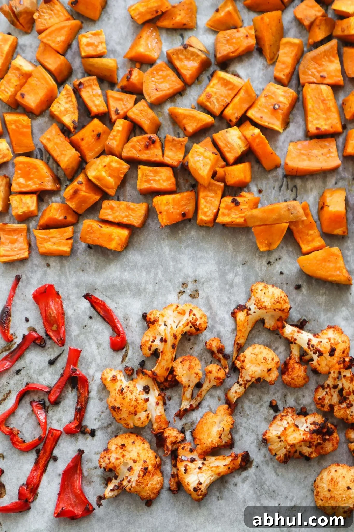 A super easy roasted vegetable recipe for spicy roasted cauliflower, sweet potatoes and a sad little red pepper. This healthy side dish recipe is great for meal prep, vegan, gluten free and paleo.