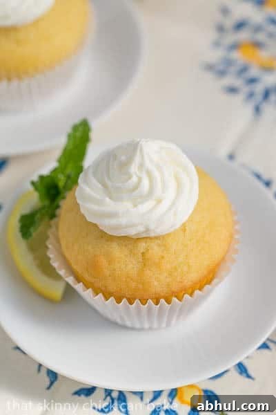 Limoncello Cupcake on a round white plate with a lemon and mint garnish.