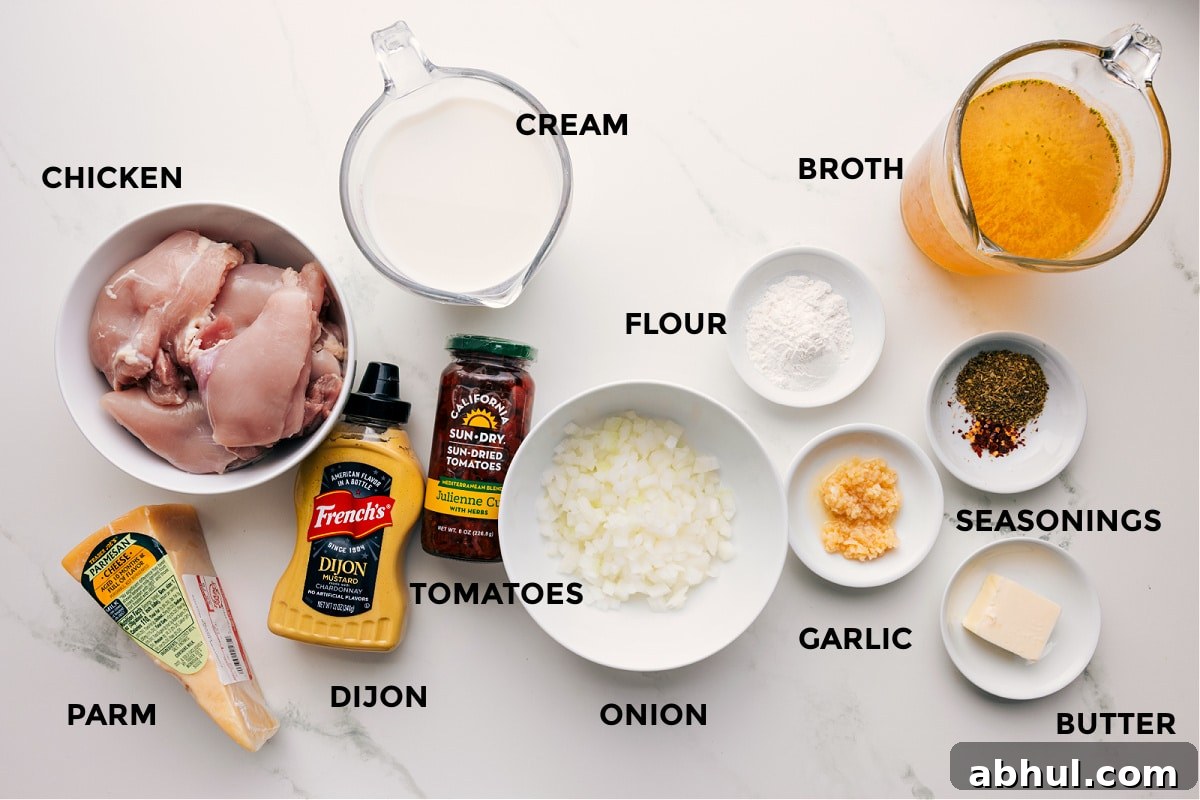 All the ingredients prepped for easy assembly, including chicken, Parmesan, Dijon, cream, tomatoes, onion, flour, garlic, seasonings, butter, and broth.
