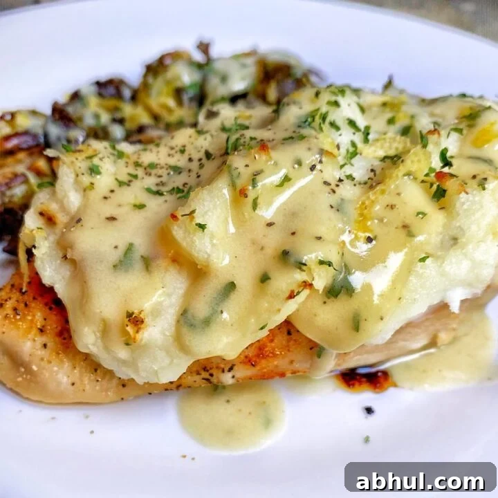 a chicken breast that has been baked and topped with mashed potatoes and then covered in a creamy béarnaise sauce