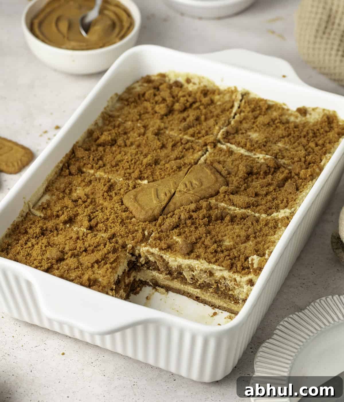 Tiramisu in a white ceramic dish with one portion taken out.