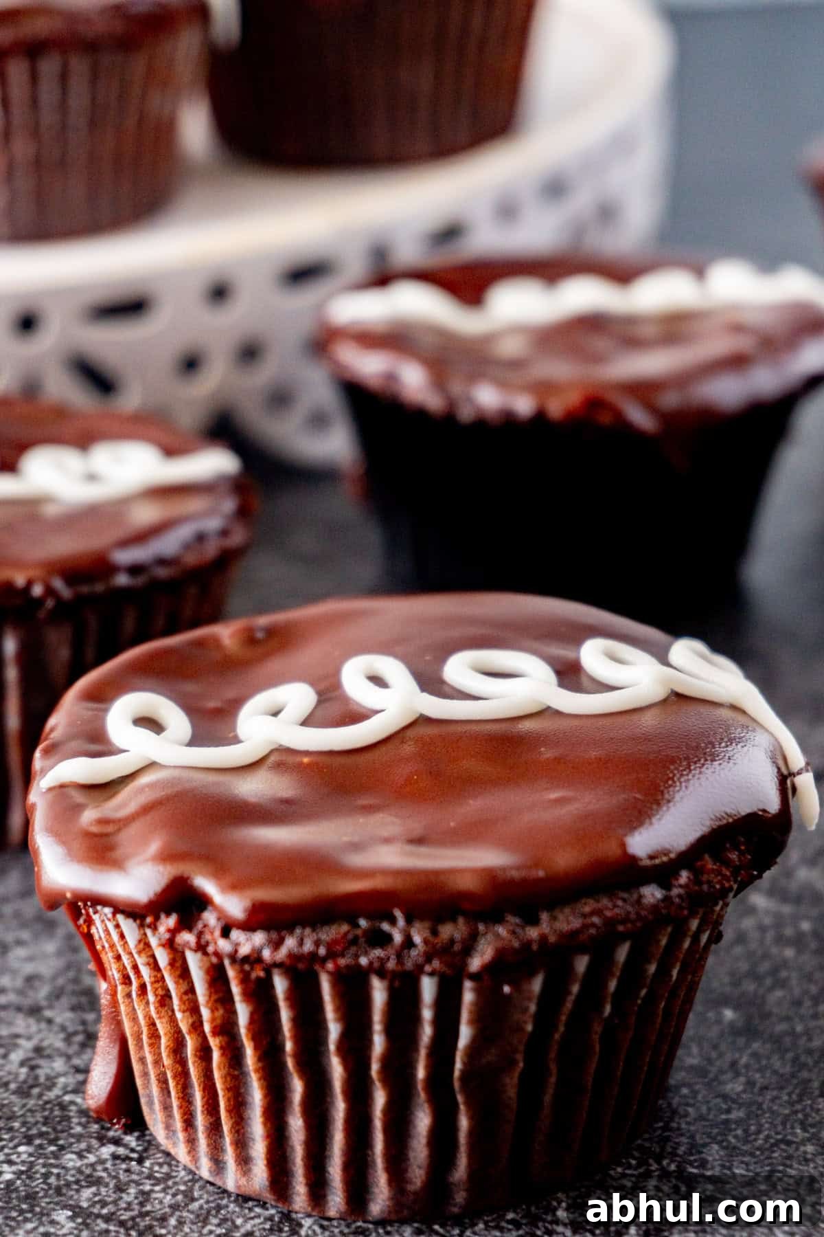Cream Filled Chocolate cupcake with shiny ganache topping and a white swirl.